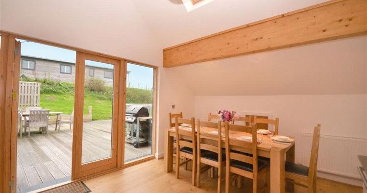 Dining area with wooden table and chairs next to large glass doors opening to a patio and grassy yard.