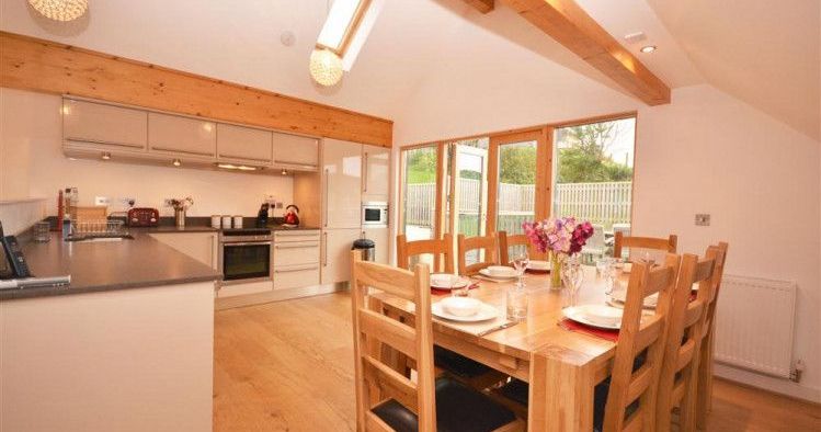 Modern kitchen and dining area with wooden beams and large windows