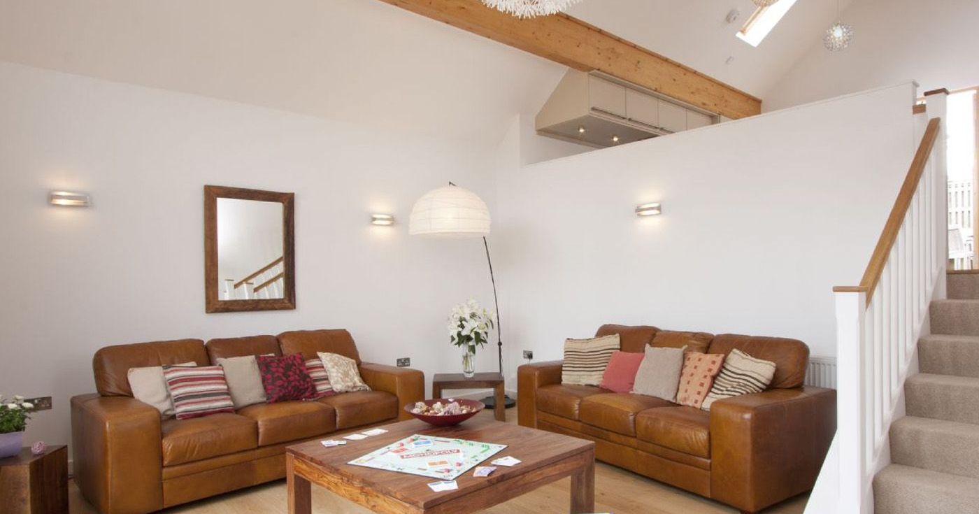 Modern living room with brown leather sofas, wooden table, and Monopoly board game.