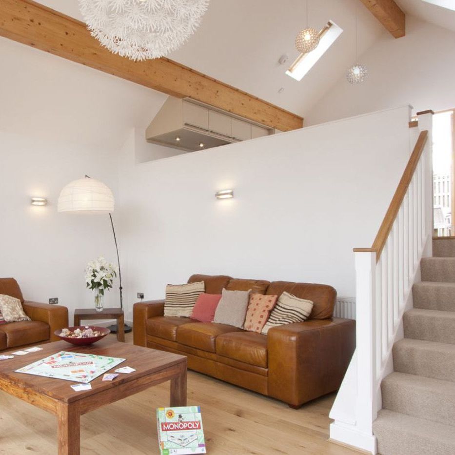Modern living room with brown leather sofas, wooden table, and Monopoly board game.
