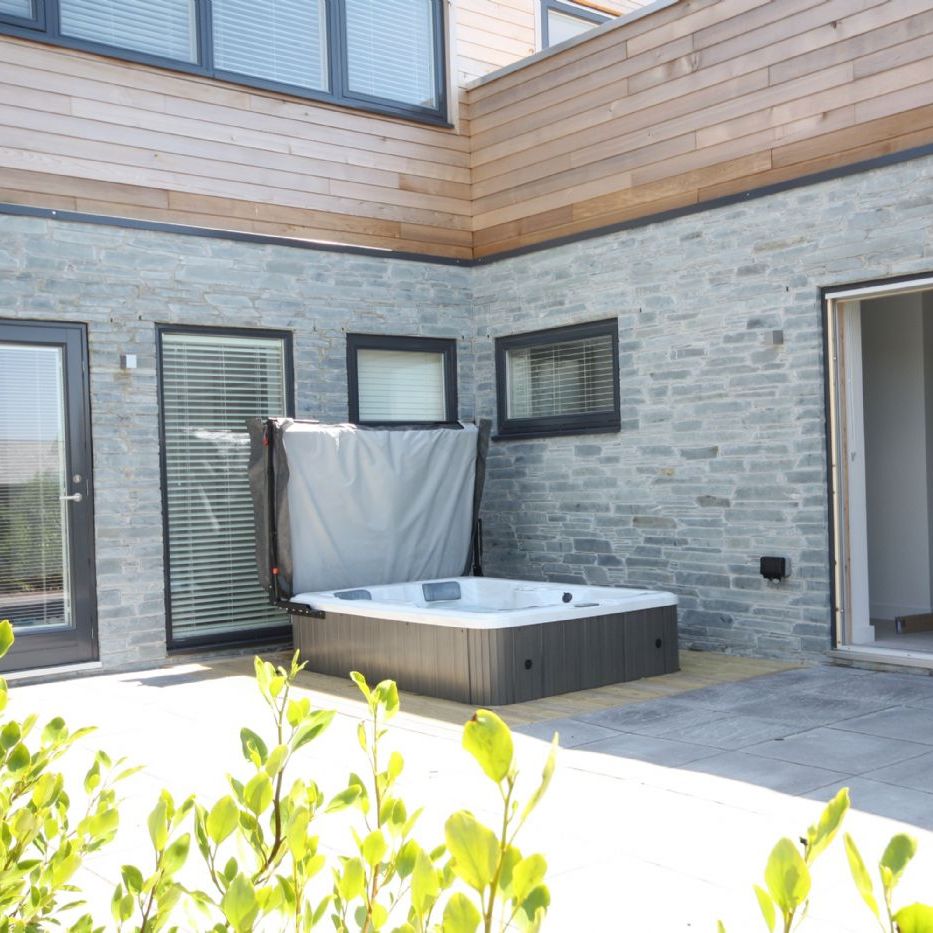 Modern patio with a hot tub and stone walls