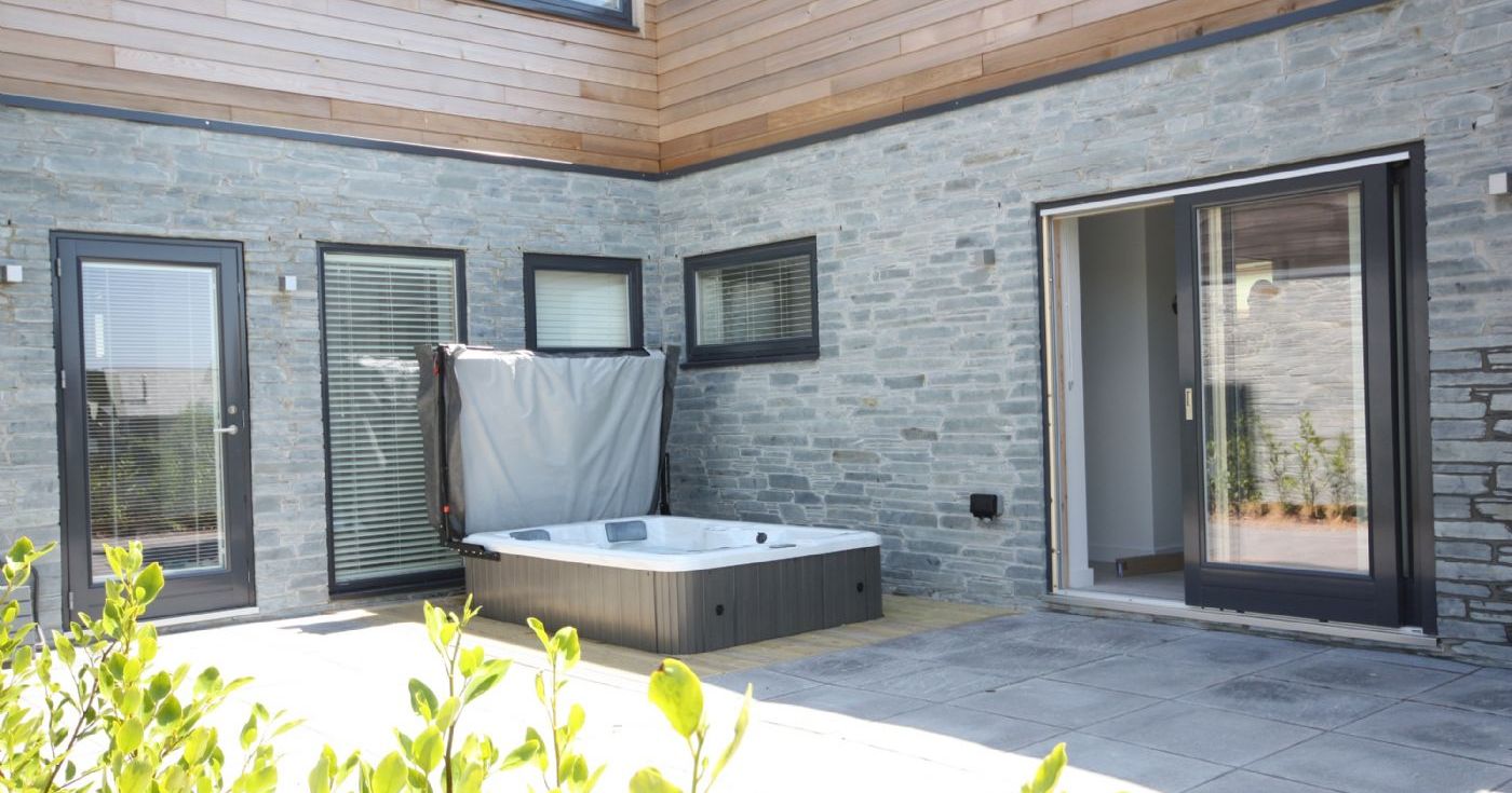 Modern patio with a hot tub and stone walls