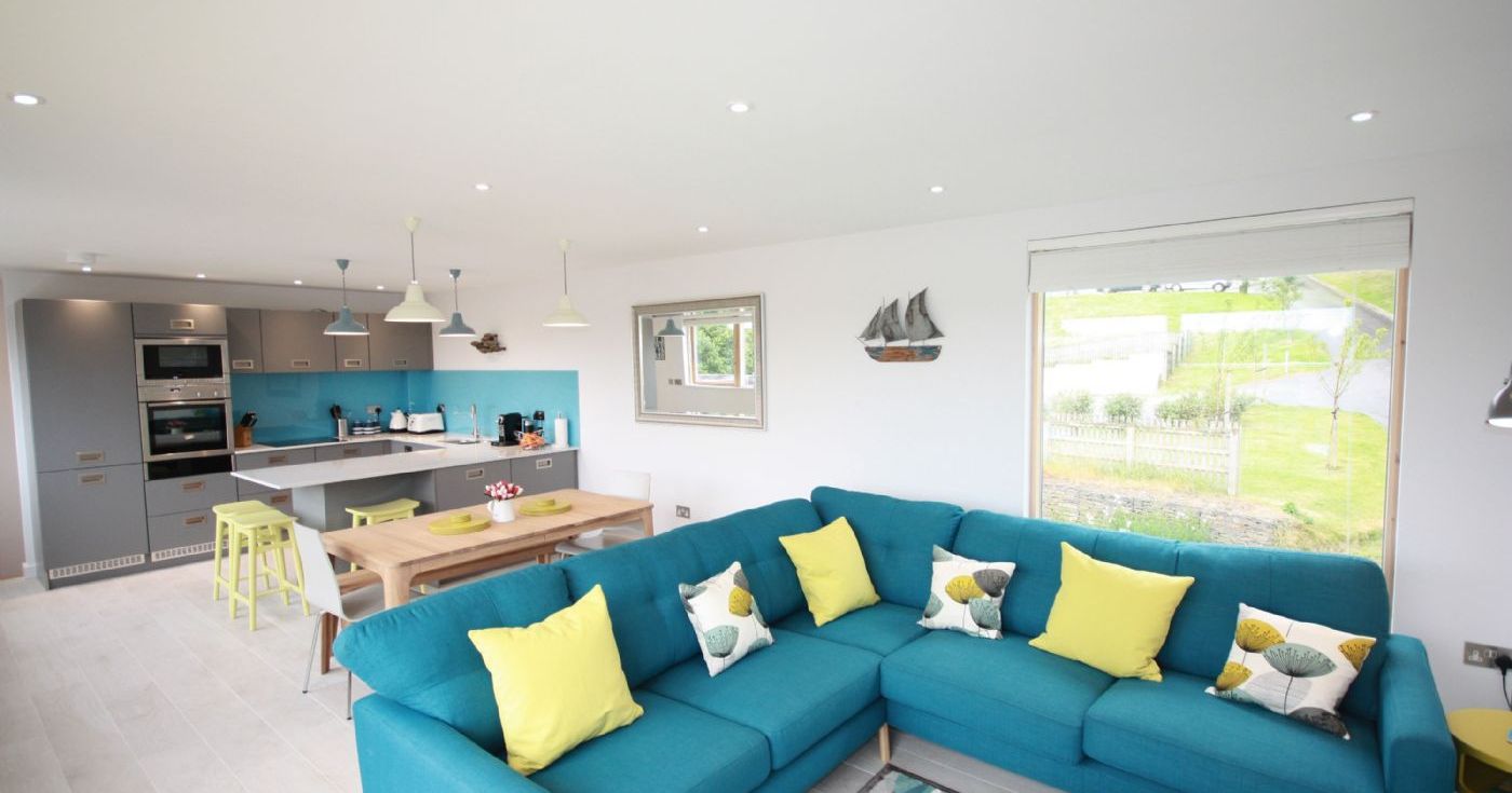 Modern open-plan living room and kitchen with blue sofa and yellow cushions
