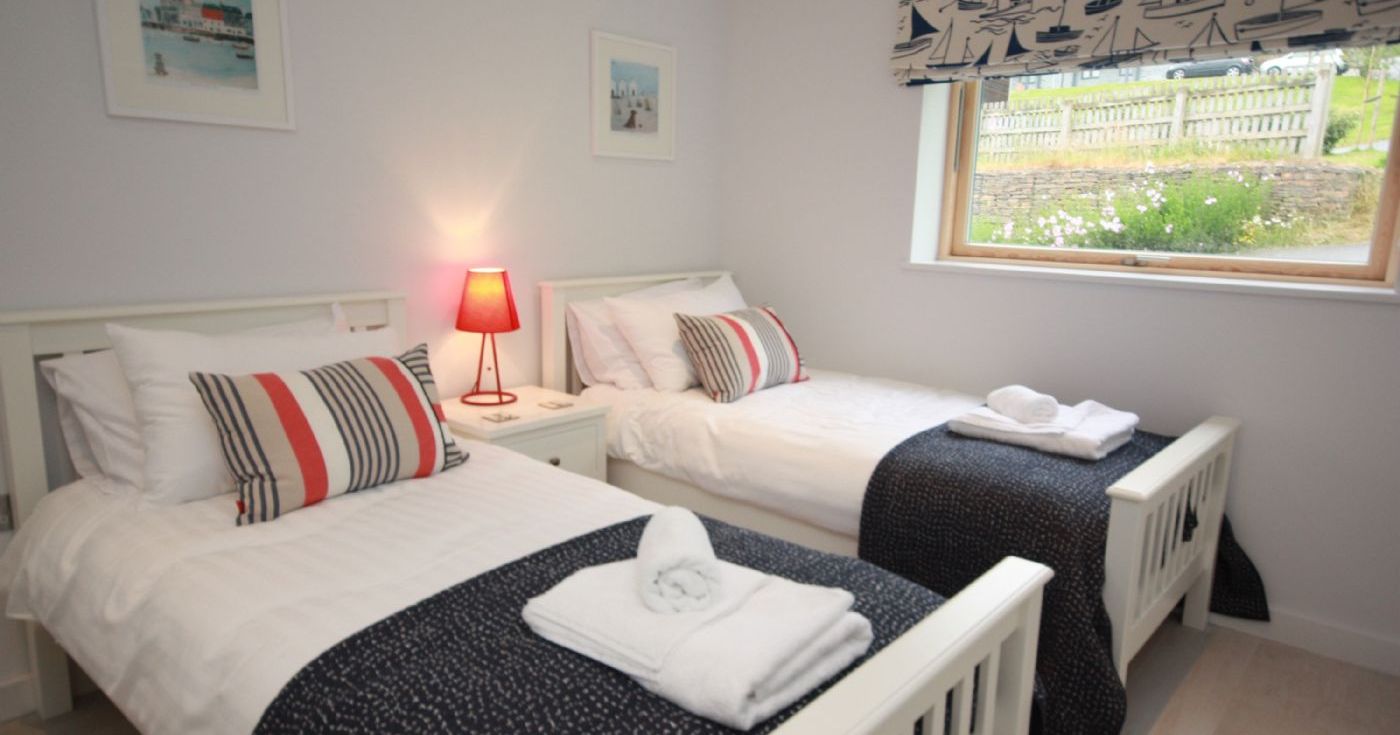 Twin bedroom with two single beds, nautical decor, and a window view