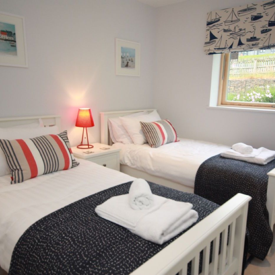 Twin bedroom with two single beds, nautical decor, and a window view