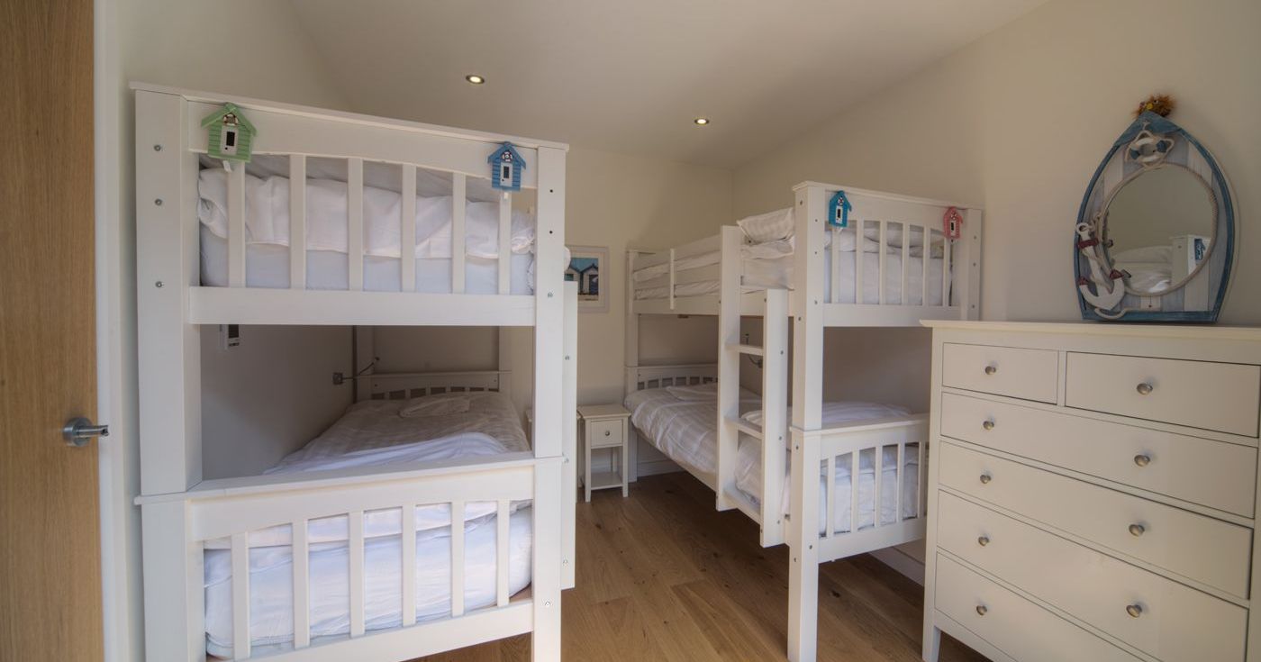 Children's bedroom with two sets of white bunk beds and a white dresser