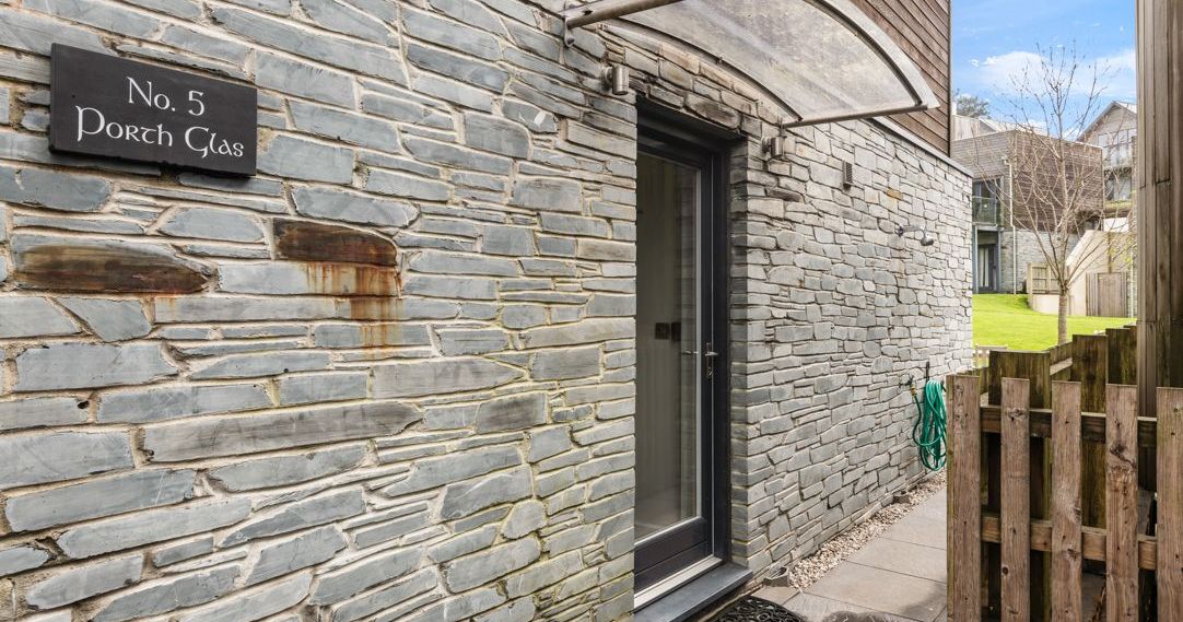 Modern stone house entrance with sign 'No. 5 Porth Glas'