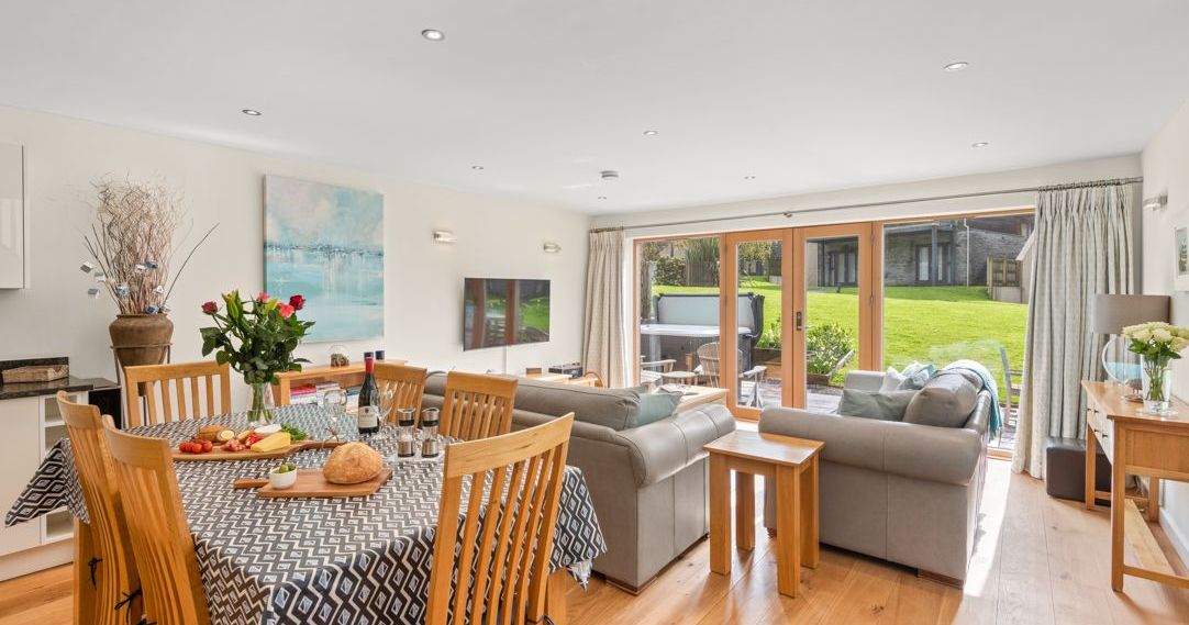 Modern open plan living and dining area with a view of a garden through large sliding glass doors.