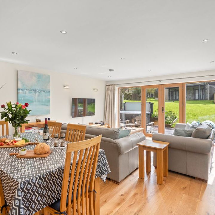 Modern open plan living and dining area with a view of a garden through large sliding glass doors.