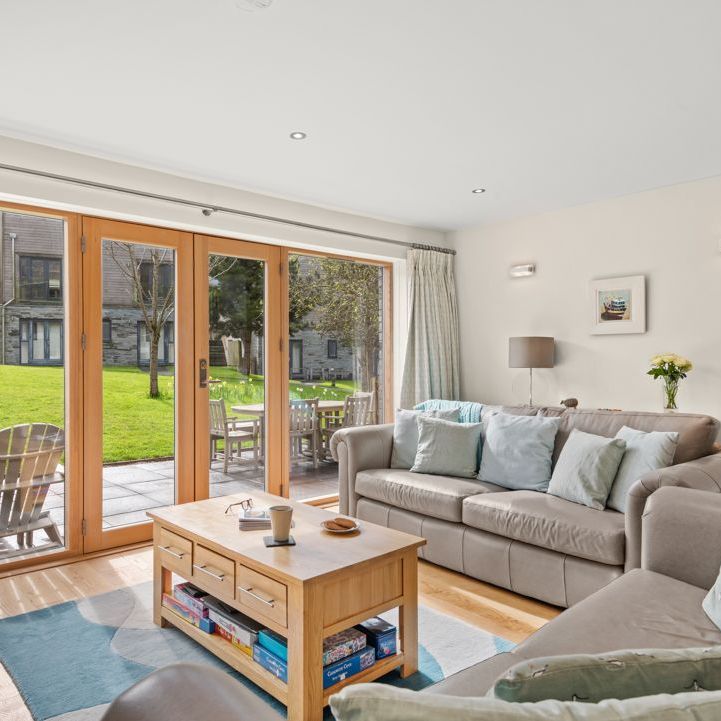 Modern living room with large glass doors opening to a patio and grassy outdoor area.
