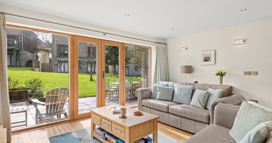 Modern living room with large glass doors opening to a patio and grassy outdoor area.