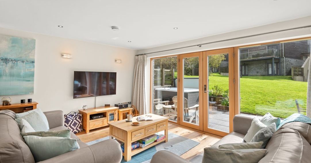 Modern living room with large glass doors opening to a patio and grassy backyard