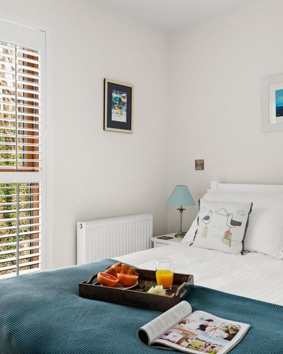 Cozy bedroom with a white bed, blue accents, and breakfast tray