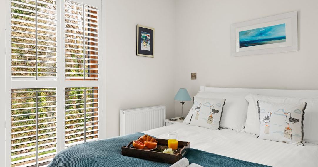 Cozy bedroom with a white bed, blue accents, and breakfast tray