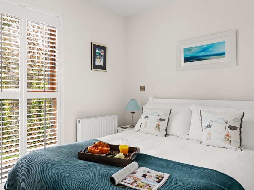 Cozy bedroom with a white bed, blue accents, and breakfast tray