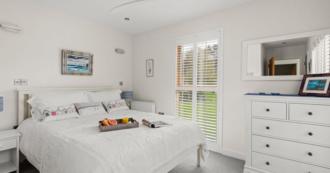 Bright bedroom with white decor, large bed, and breakfast tray