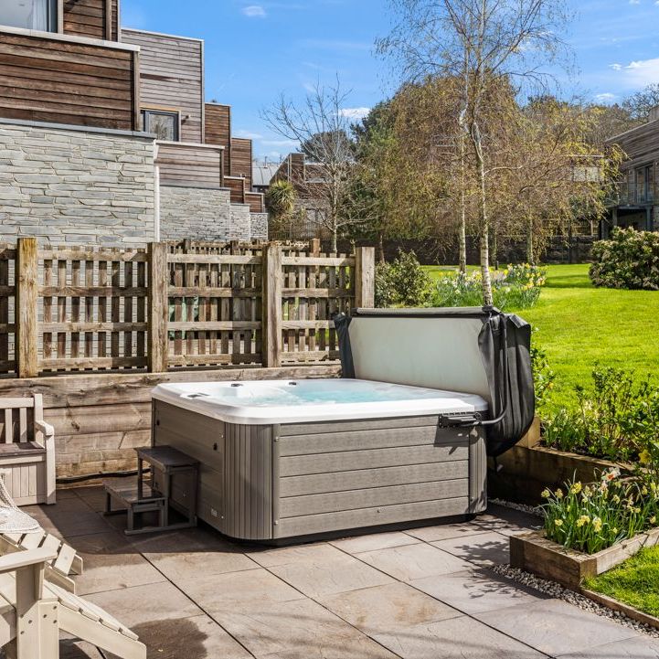 Outdoor hot tub on a patio with garden and wooden fence
