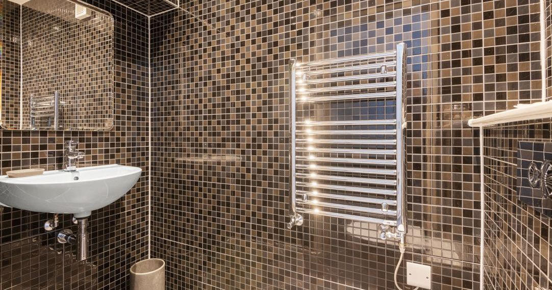Modern bathroom with brown mosaic tiles and chrome towel warmer
