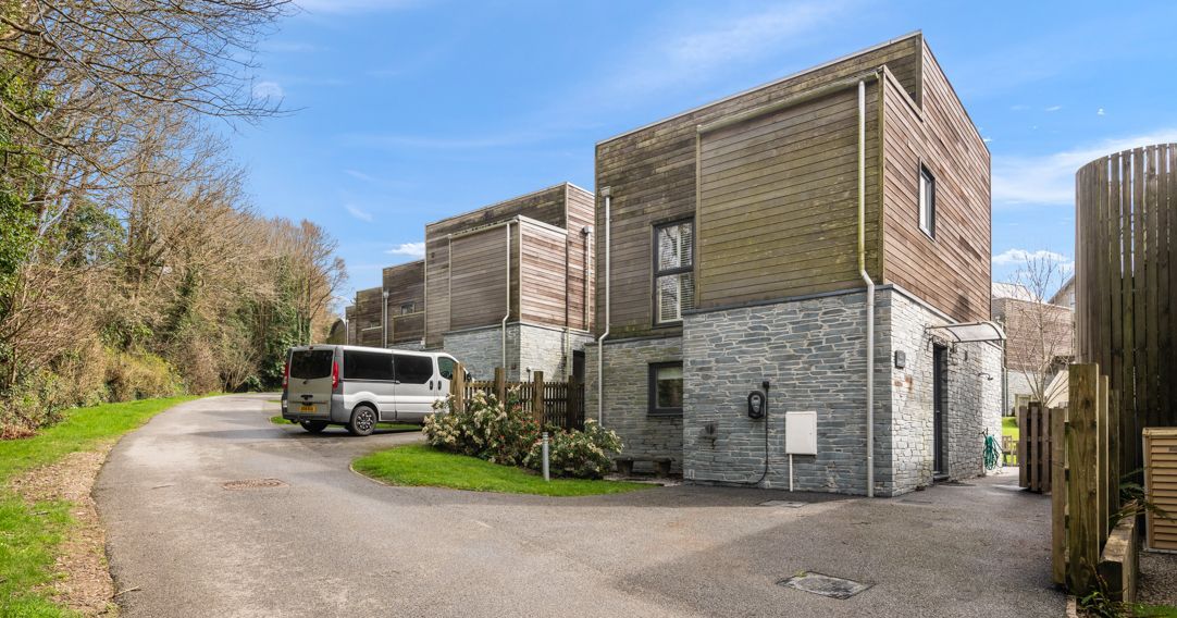 Modern houses with stone and wood exterior along a curved driveway with a parked van