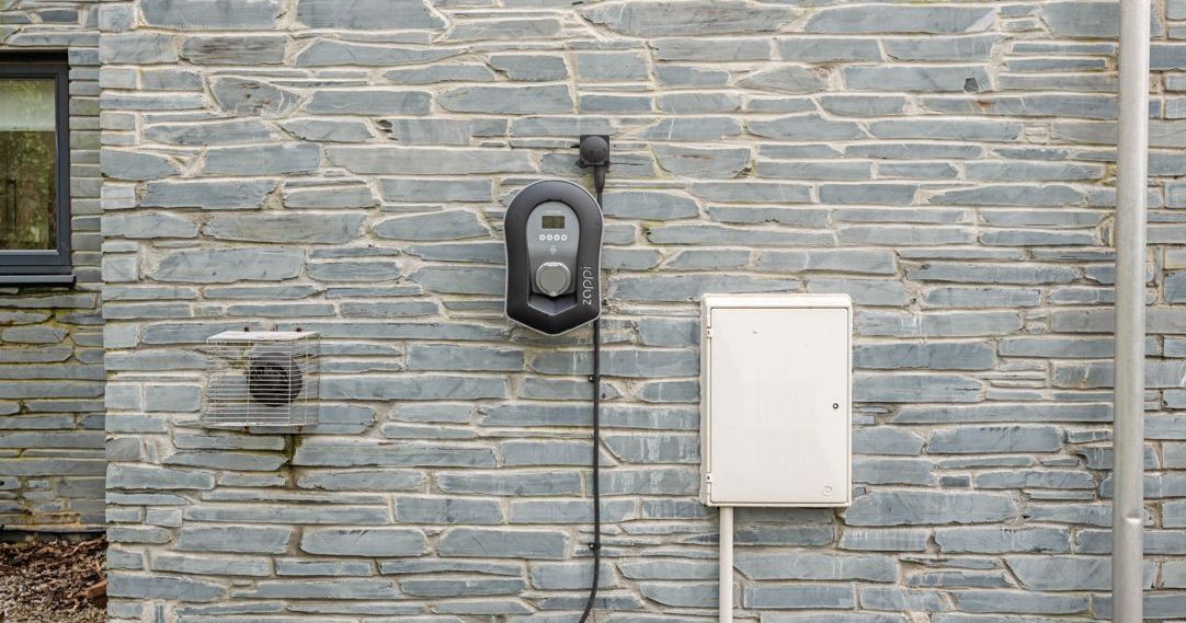 Electric vehicle charger mounted on a stone wall outside a building