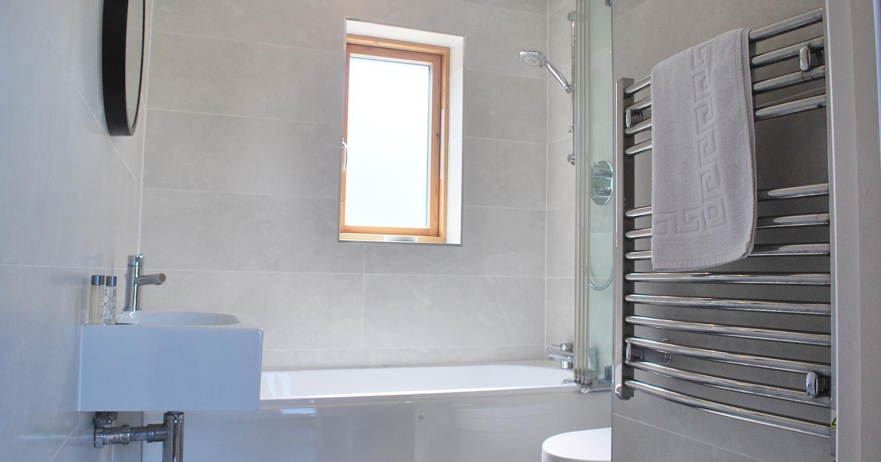 Modern bathroom with bathtub, towel rail, and small window