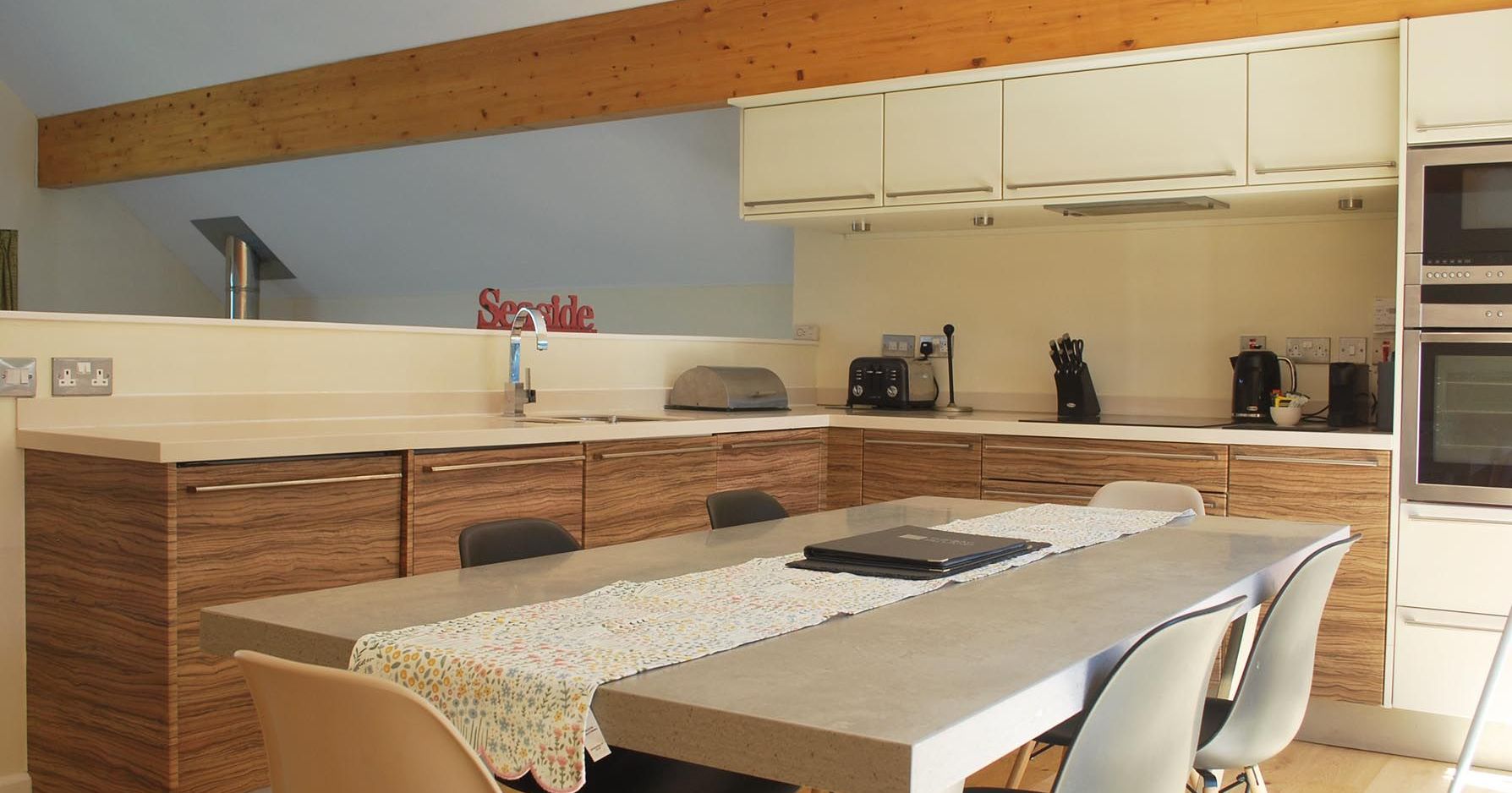 Modern kitchen with wooden cabinets, minimalist decor, and dining table with chairs