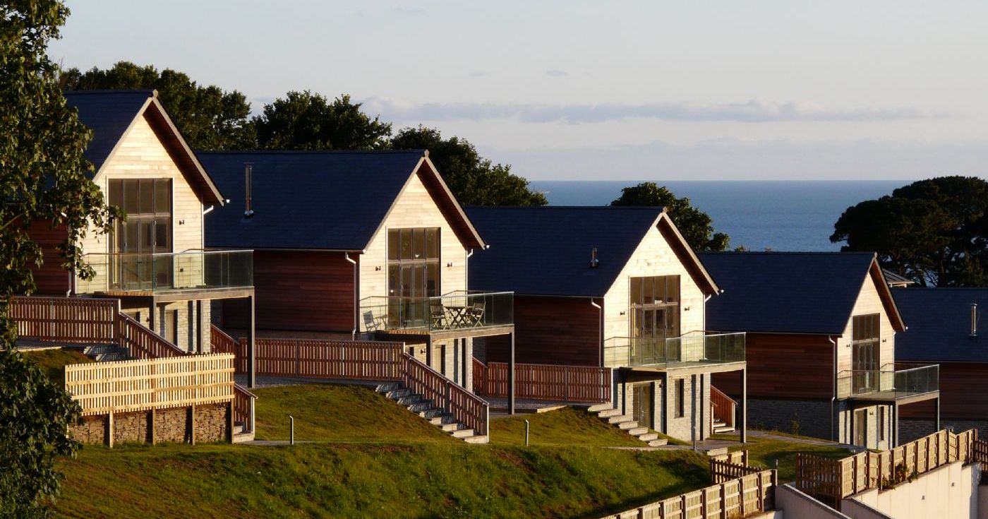 Modern wooden houses on a hill with sea view in the background