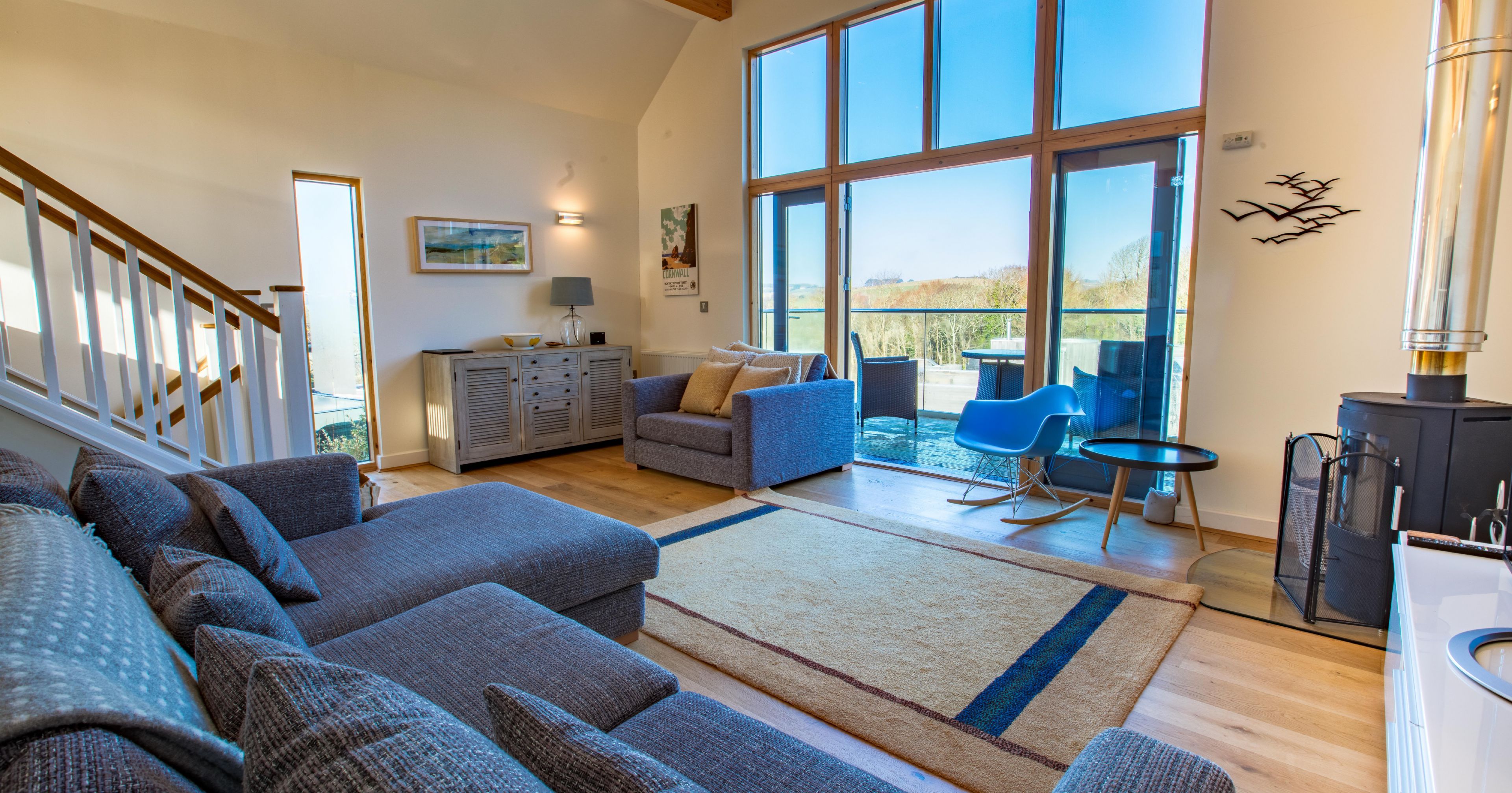 Modern living room with large windows, grey couch, and patio view