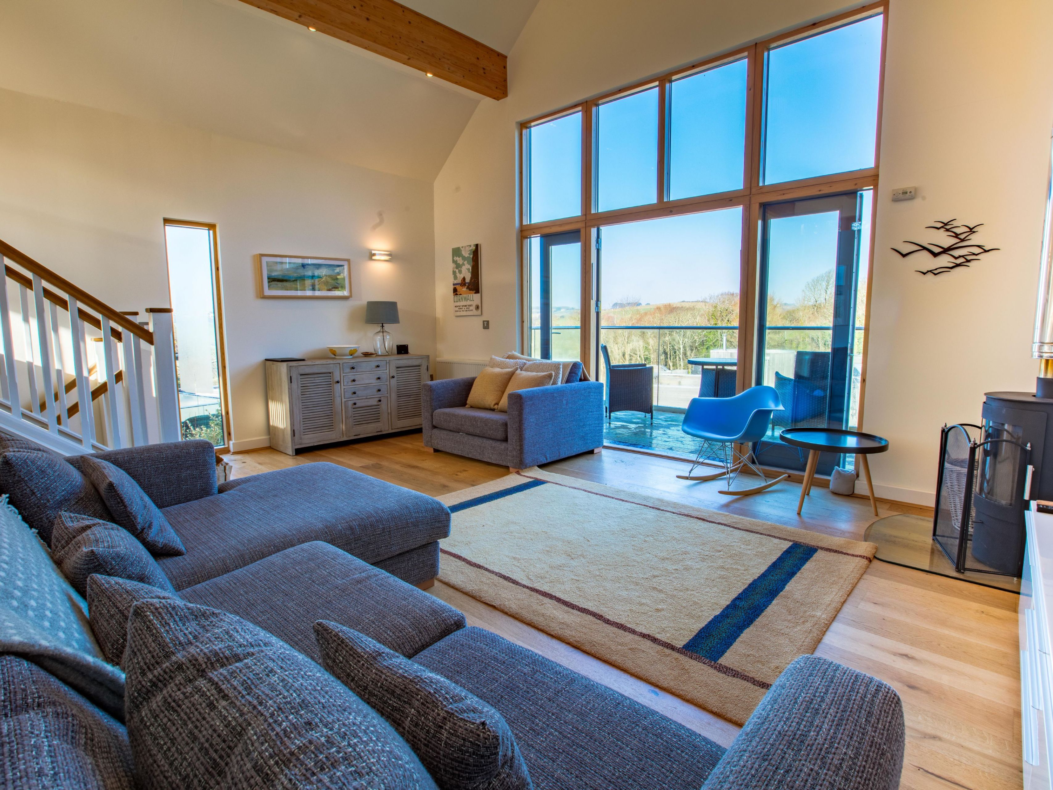 Modern living room with large windows, grey couch, and patio view