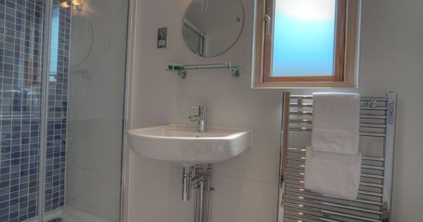 Modern bathroom with a shower, sink, round mirror, window, and towel rack