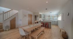 Modern open-plan kitchen and dining area with wooden flooring and minimalist decor