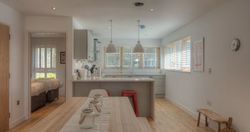 Modern open-plan kitchen and dining area with wooden floors and light decor