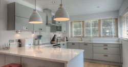 Modern kitchen with grey cabinets, white countertops, and pendant lights