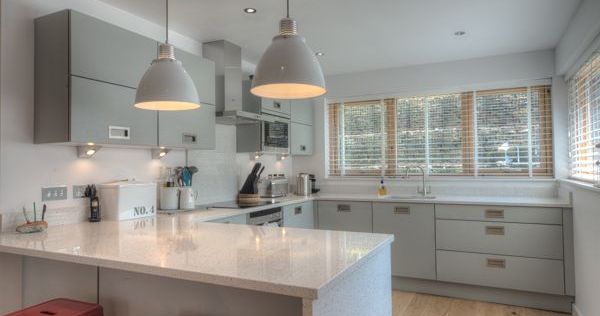 Modern kitchen with grey cabinets, white countertops, and pendant lights