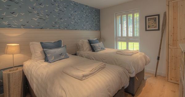 Cozy bedroom with two single beds, blue and white decor, and a seagull wallpaper accent wall.