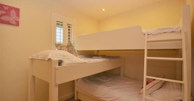 Small room with a white bunk bed and a ladder