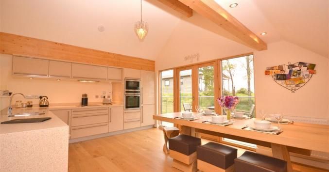 Modern kitchen and dining area with wooden beams, large table, and light wood flooring