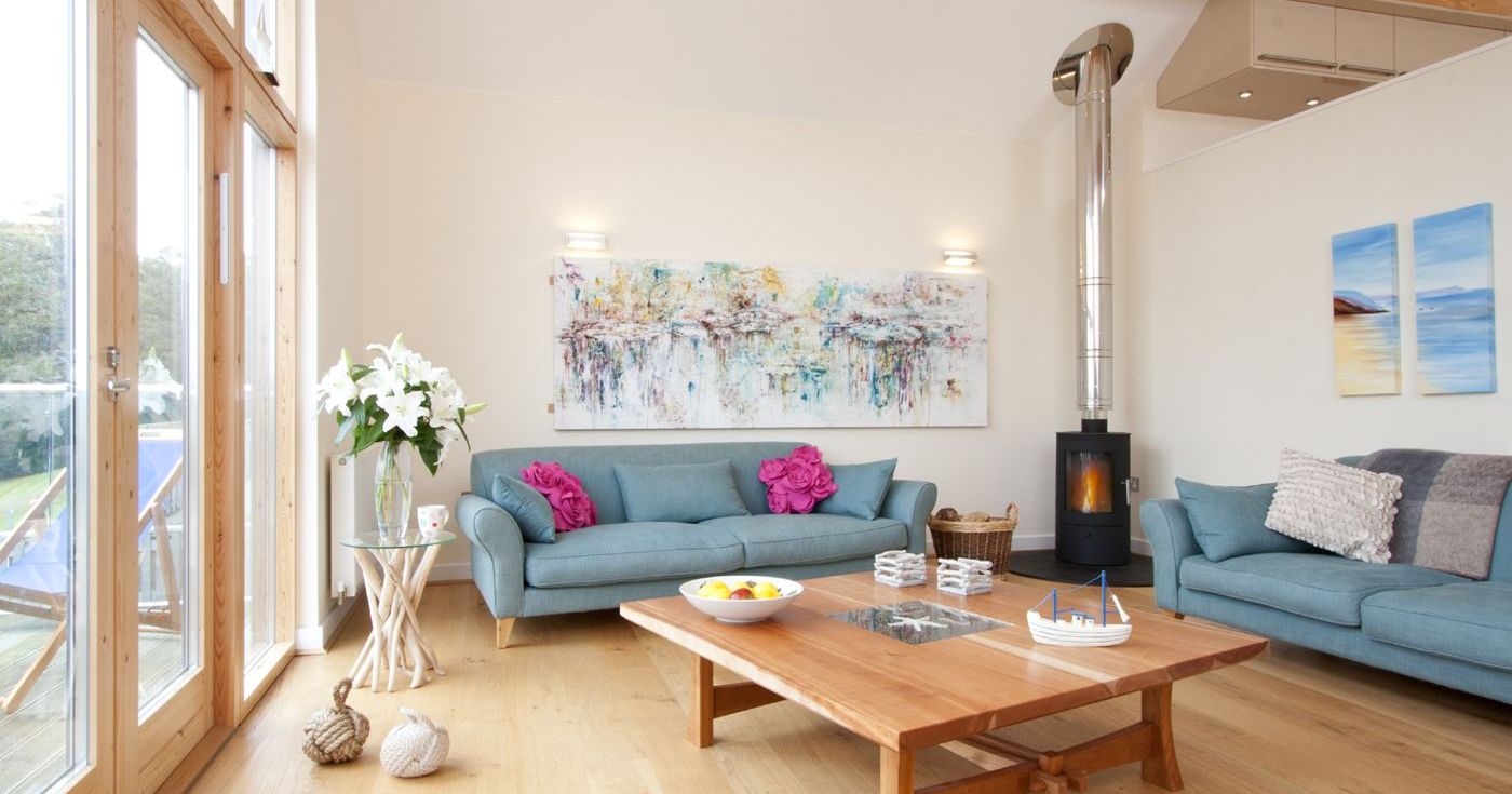 Bright living room with wooden floors, blue sofas, and large windows