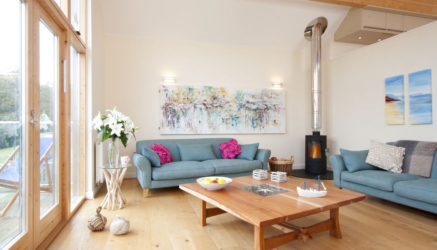 Bright living room with wooden floors, blue sofas, and large windows