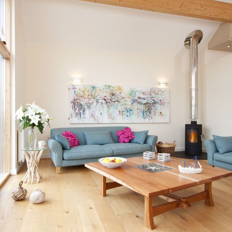 Bright living room with wooden floors, blue sofas, and large windows