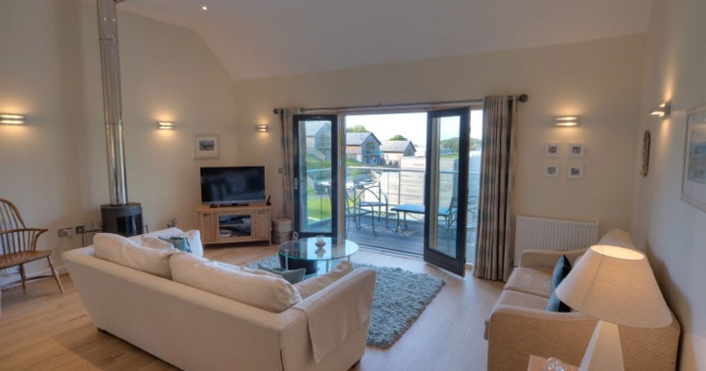 Modern living room with large sliding glass doors opening to a balcony and outdoor seating.