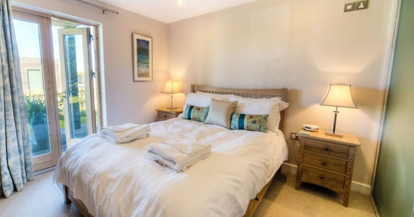 Cozy bedroom with double bed, bedside tables, lamps, and open doors to a patio