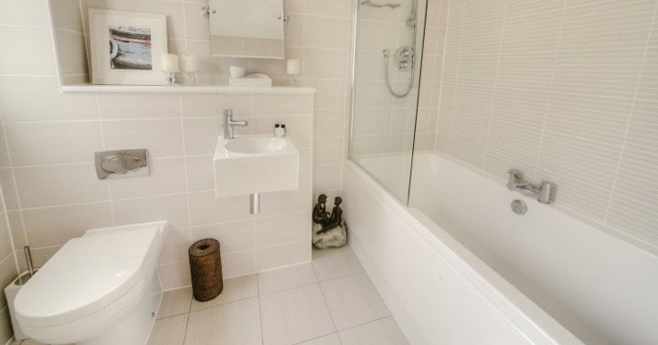 Modern white bathroom with bathtub, toilet, and small sink.
