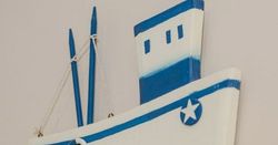 Decorative wooden boat wall hanging with blue and white accents and a small fish ornament