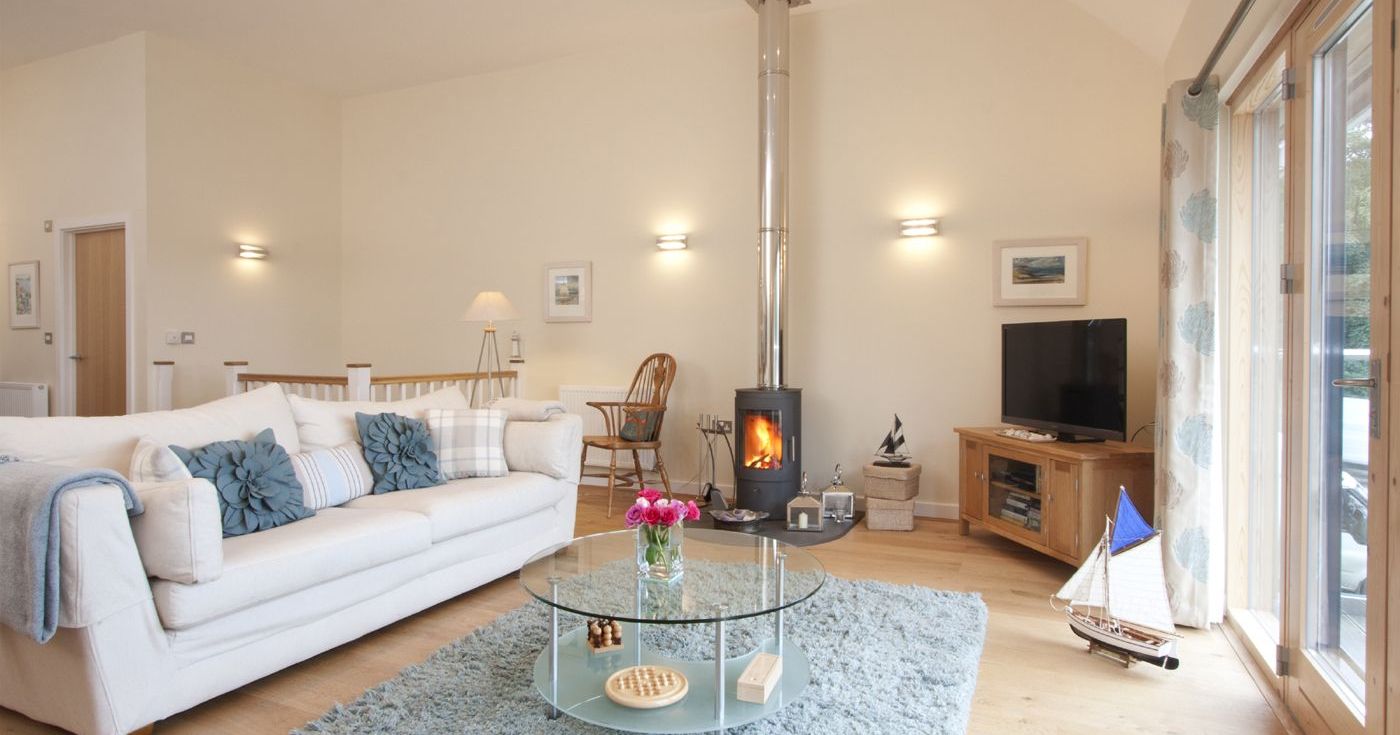 Modern living room with light decor, wood stove, and glass coffee table