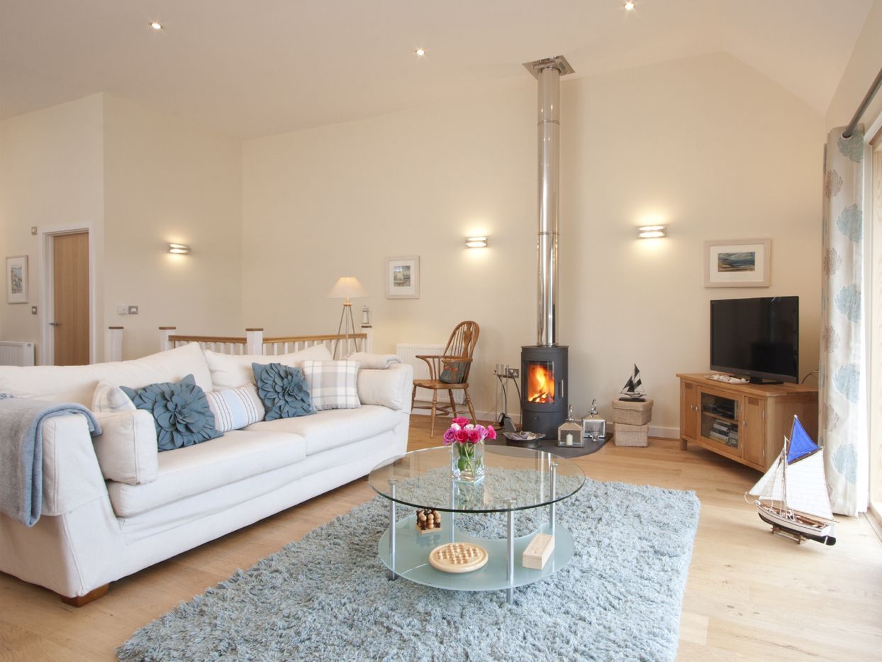 Modern living room with light decor, wood stove, and glass coffee table