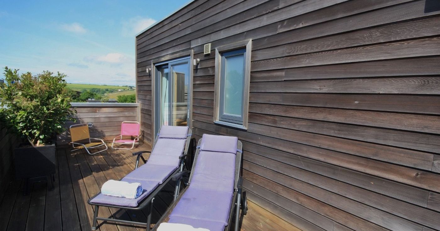 Modern wooden rooftop terrace with lounge chairs and countryside view