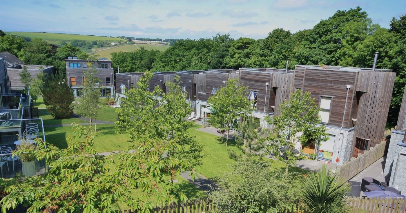 Modern eco-friendly houses with wooden exteriors surrounded by lush greenery and gardens