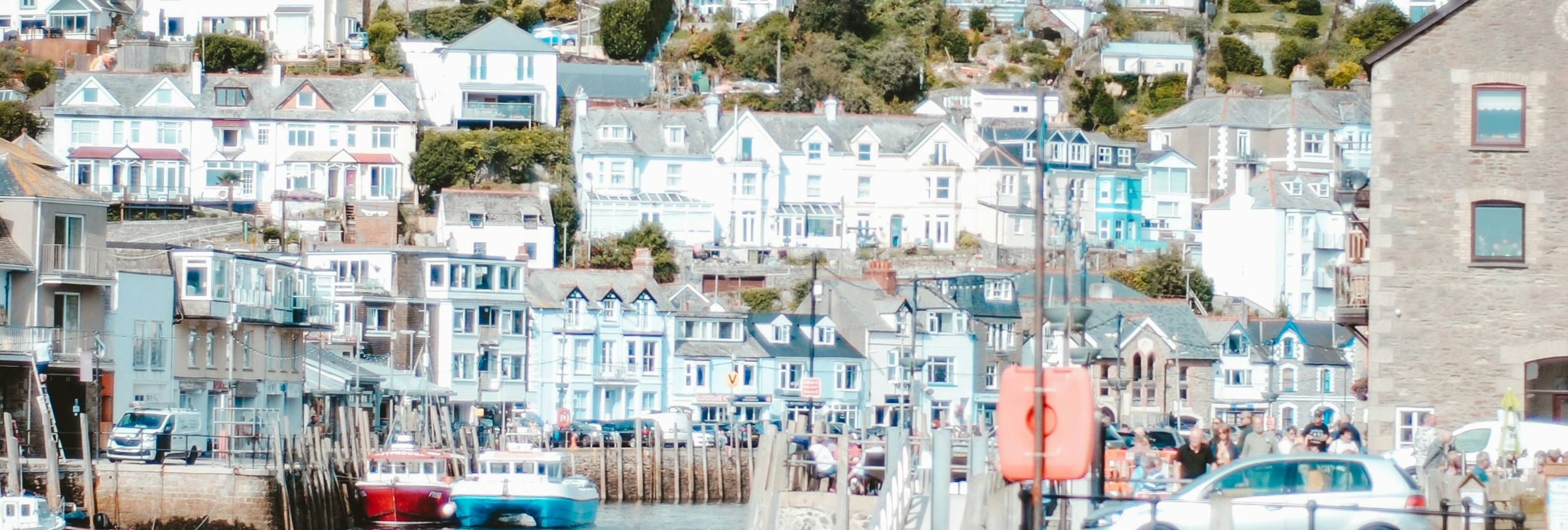 Quaint seaside town with hilltop houses and a small harbor with boats.