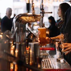 Bartender pouring a glass of beer from a tap at a busy bar